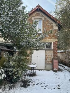 una casa con una mesa delante de ella en la nieve en Cosy Maisonette Versailles, en Versalles