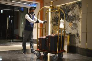 a man is standing next to a luggage cart at Clouds Hotel in Medina