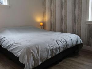 Ce lit se trouve dans une chambre dotée d'un couvre-lit blanc. dans l'établissement Holiday home LEUK, à Callantsoog