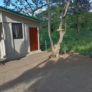 ein kleines Haus mit einem Baum daneben in der Unterkunft Camping Mena’s in La Cruz