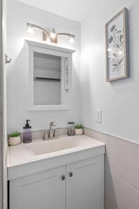 a white bathroom with a sink and a mirror at Warm Villa 1 block to Mary Washington Campus in Fredericksburg