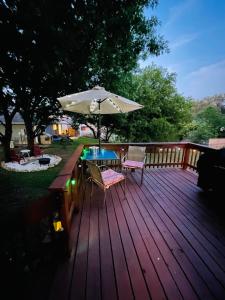 a wooden deck with an umbrella and a table and chairs at Lost Bluff Casa in San Antonio