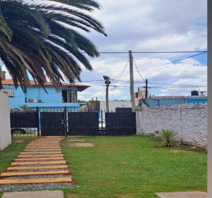 einen Hof mit einem Zaun und einer Palme in der Unterkunft Hostal La Palmera in Ezeiza