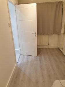 an empty room with a white door and wooden floor at Ensuite room in Thamesmead