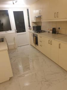 a kitchen with white cabinets and a marble floor at Ensuite room in Thamesmead