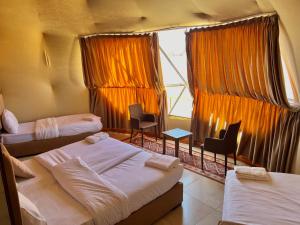 una camera con tre letti e sedie e una finestra di Wadi Rum living camp a Wadi Rum