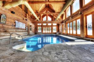 een binnenzwembad in een houten huis met ramen bij Chalet Silver Fox SPA at Fiddler's Lake in Mille-Isles