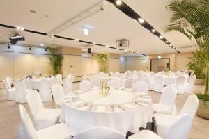 un salón de banquetes con mesas blancas y sillas blancas en Ramada by Wyndham Yongin en Yongin