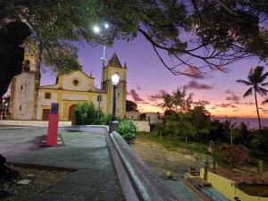 a church with a clock tower in front of the ocean at Cantinho das Olandas in Olinda