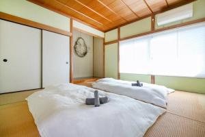 湯河原「ゲストハウス城堀の家」 في يوغاوارا: سريرين في غرفة مع نافذة كبيرة