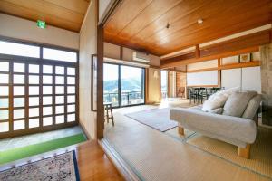 ein Wohnzimmer mit einem Sofa und einigen Fenstern in der Unterkunft 湯河原「ゲストハウス城堀の家」 in Yugawara