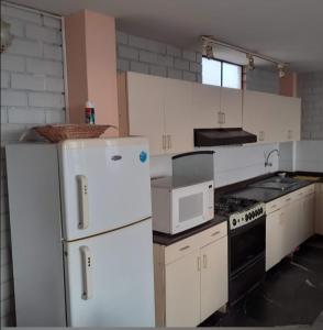 a kitchen with white appliances and white cabinets at Alojamiento Punta Negra in Punta Negra