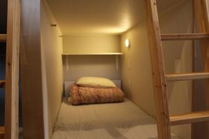 Hostel Wasabi Asakusa في طوكيو: غرفة نوم صغيرة مع سرير بطابقين في غرفة