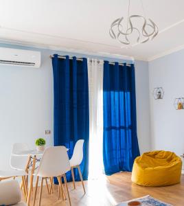 een woonkamer met blauwe gordijnen en een tafel en stoelen bij Cane Apartment New Bazaar in Tirana