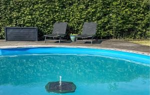 two chairs and a swimming pool with a fountain at Nice Home In storp With Kitchen in Åstorp