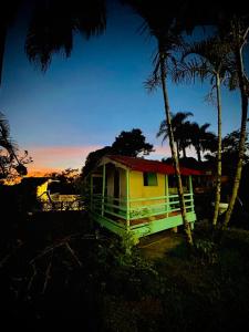 ein gelbes Haus mit einem roten Dach neben Palmen in der Unterkunft Chácara Goufran in Caçapava