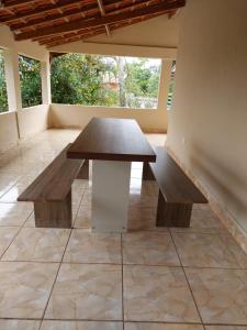 einen Tisch und Bänke in einem Zimmer mit einem großen Fenster in der Unterkunft Chácara Goufran in Caçapava