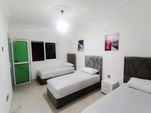 2 letti in una camera con pareti e finestre bianche di Fantastique Appartement Nouveau meublé avec WIFI & NETFLIX à proximité du MARJANE M2 a Tangeri