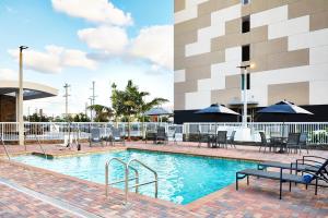 een zwembad met tafels en stoelen en een gebouw bij Fairfield Inn & Suites by Marriott Miami Airport West/Doral in Miami