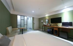 um quarto de hotel com uma cama grande e uma televisão em Yeonsan Oops Hotel em Busan