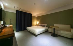 1 dormitorio con cama, mesa y sofá en Yeonsan Oops Hotel en Busan