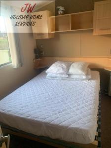 uma cama com lençóis brancos e almofadas num quarto em Shorni's Retreat em Great Driffield