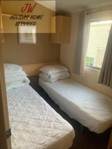 Duas camas num pequeno quarto com uma janela em Shorni's Retreat em Great Driffield
