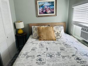 a bedroom with a bed with a blanket and pillows at Across bridge to Palm Beaches! Great Price for 3 Bedroom House! Sleeps 5 Fenced Backyard Deck Grill Firepit!Close to Downtown in Lake Worth