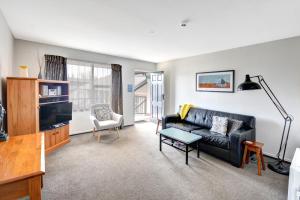 a living room with a black couch and a tv at Alexis Motor Lodge in Dunedin