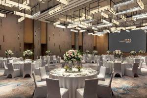 深セン市にあるCourtyard by Marriott Shenzhen Bayの白いテーブルと椅子、シャンデリアが備わる会議室