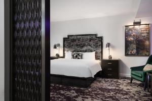 a bedroom with a bed and a green chair at JW Marriott Savannah Plant Riverside District in Savannah