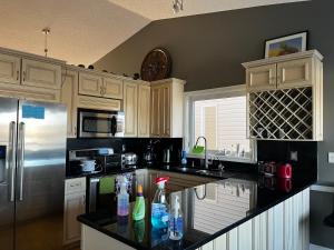 a kitchen with black counter tops and a refrigerator at Citadel hill cr community! in Calgary