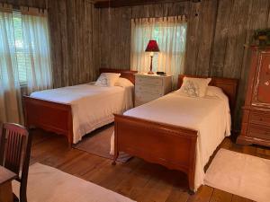2 camas en un dormitorio con paredes de madera y suelo de madera en Mary's Place - Studio surrounded by nature but close to High Point, en High Point