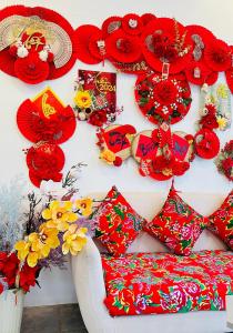 a wall with red flowers and red umbrellas at Sele House in Hà Tiên