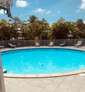 a large blue swimming pool with chairs and trees at Le Grey House in Saint-François