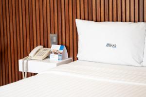 - un lit avec un téléphone sur une table à côté d'un lit dans l'établissement Hotel Atenas, à Xalapa
