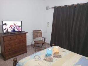 Schlafzimmer mit einem Bett, einem TV und einer Kommode in der Unterkunft JOAQUINA in Ramallo