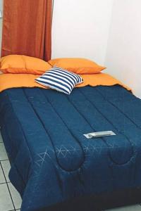 1 cama azul con edredón azul y almohadas de color naranja en Departamento Completo, Centro Histórico Durango, en Durango