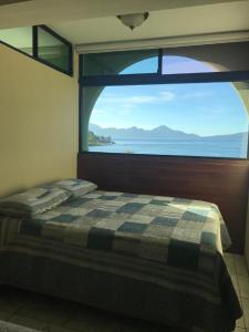 a bed in a room with a large window at Apartamento Torres de Atitlan in Panajachel
