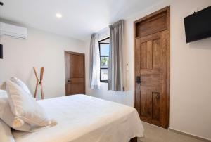 a bedroom with a white bed with a wooden door at Casa Irake in Guadalajara