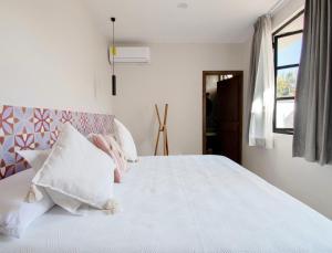 a bedroom with a white bed with pink and white pillows at Casa Irake in Guadalajara