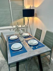a table with plates and wine glasses on it at Cosy 3 bedroom Near Heathrow - 6 beds, sleeps 7, FREE PARKING in Staines upon Thames