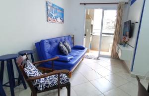 ein Wohnzimmer mit einem blauen Sofa und Stühlen in der Unterkunft Apartamento 1 Novíssimo e Bem Localizado - Itaguá - UBATUBA-SP in Ubatuba