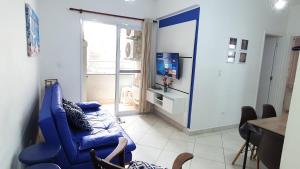 ein Wohnzimmer mit einem blauen Sofa und einem TV in der Unterkunft Apartamento 1 Novíssimo e Bem Localizado - Itaguá - UBATUBA-SP in Ubatuba