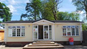 a small yellow house with white windows and stairs at Moffat Manor Holiday Resort in Beattock