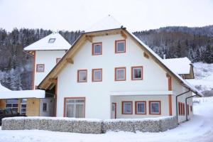 Une grande maison blanche avec de la neige au sol dans l'établissement Appartementhaus Hochegg, à Lachtal