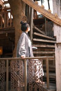 a woman standing on a fence next to a tree at Baan Boo Loo Village- SHA Plus in Chiang Mai