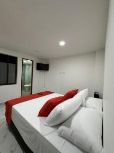 a bedroom with a white bed with red and white pillows at HOSPEDAJE TRIANON in Envigado