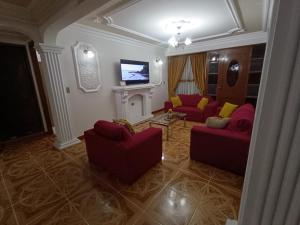 a living room with two red chairs and a tv at Para familias con niños in Sucre