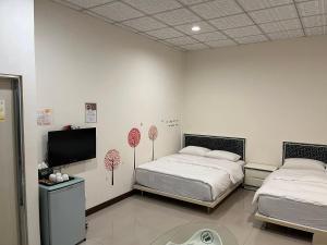 1 Schlafzimmer mit 2 Betten und einem Flachbild-TV in der Unterkunft 日升咖啡民宿 in Gukeng